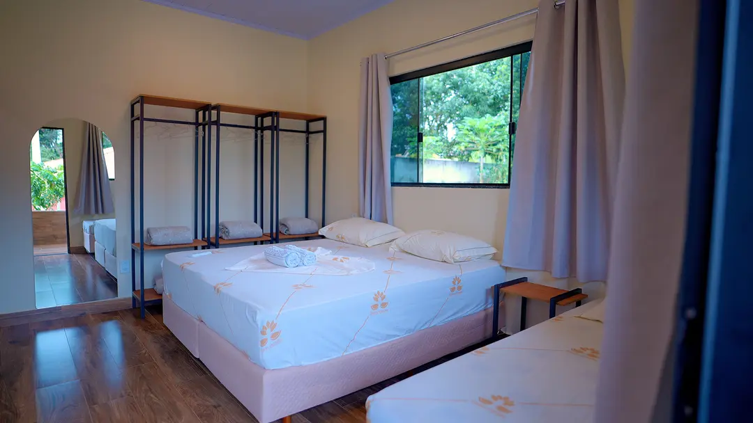Quarto do bloco Sabiá com camas arrumadas e enxoval claro