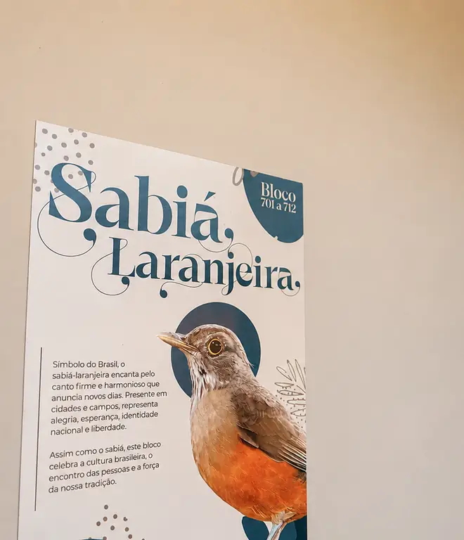 Placa do bloco Sabiá Laranjeira na entrada das suítes, com ilustração do pássaro