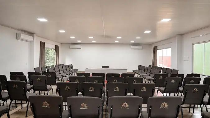 Sala de médio porte com poltronas estofadas e mesa diretora