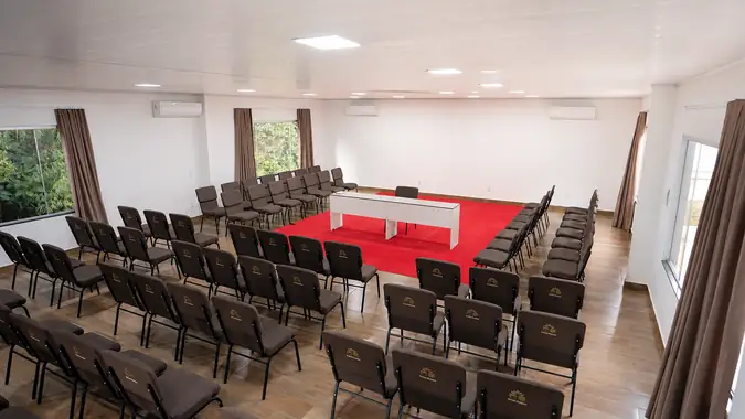Sala paralela com poltronas em torno do tapete vermelho e mesa diretora