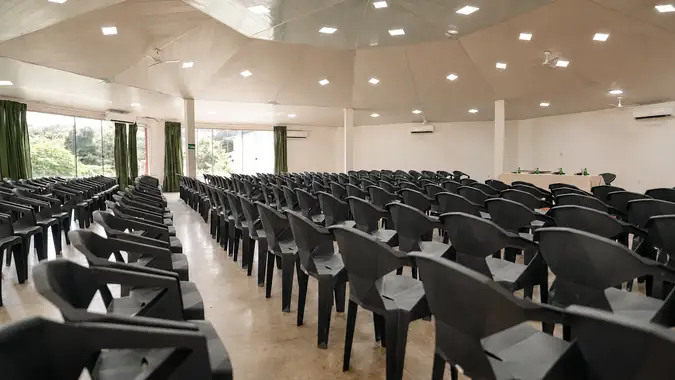 Auditório Tucano com cadeiras pretas em fileiras e cortinas verdes