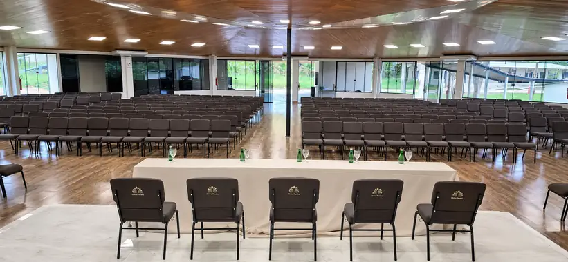Auditório Tuiuiú com mesa diretora, piso de madeira e vista para o verde