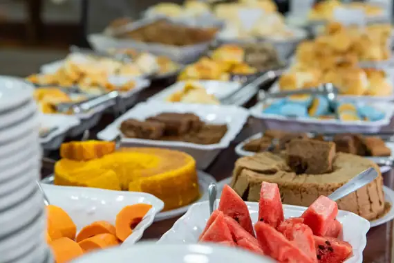 Mesa de café da manhã farta, com bolos e frutas